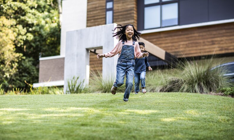 Kinder spielen auf grünem Rasen im Garten | ©  Getty Images/ MoMo Productions