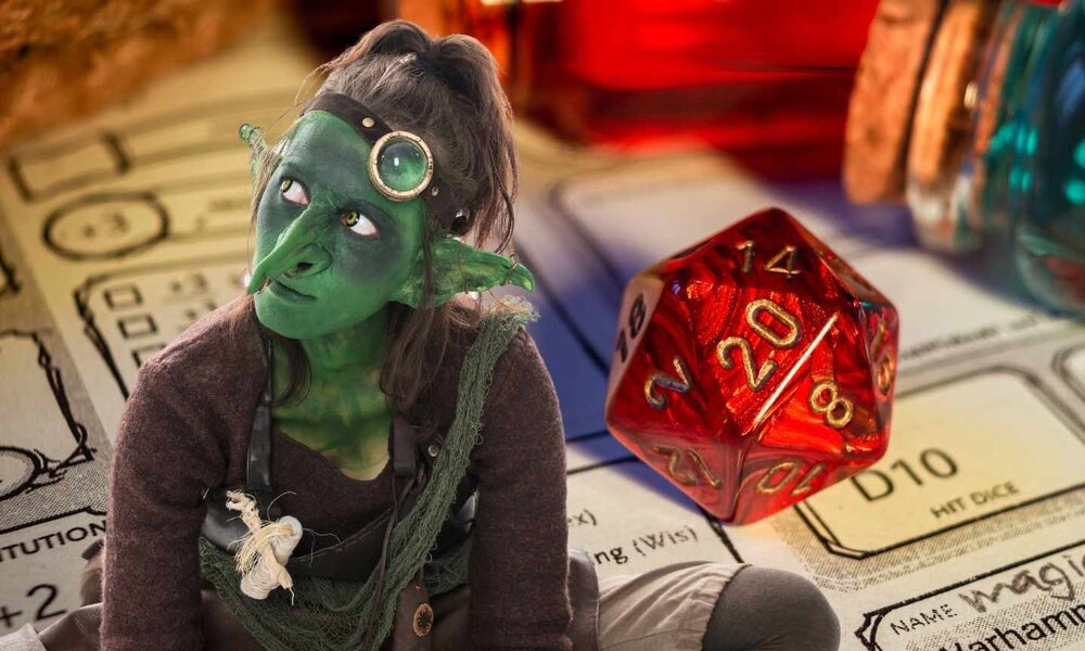 Kostümierte Spielerin mit grüner Gesichtsbemalung und Monokel überlegt ihren nächsten Zug im Rollenspiel. | © M.Dörr & M.Frommherz (vorne) + Esther  (HG) /stock.adobe.com