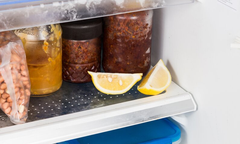 Aufgeschnittene Zitronenstücke neben Gläsern mit eingemachten Soßen im Kühlschrank. | © Getty Images/ ThamKC