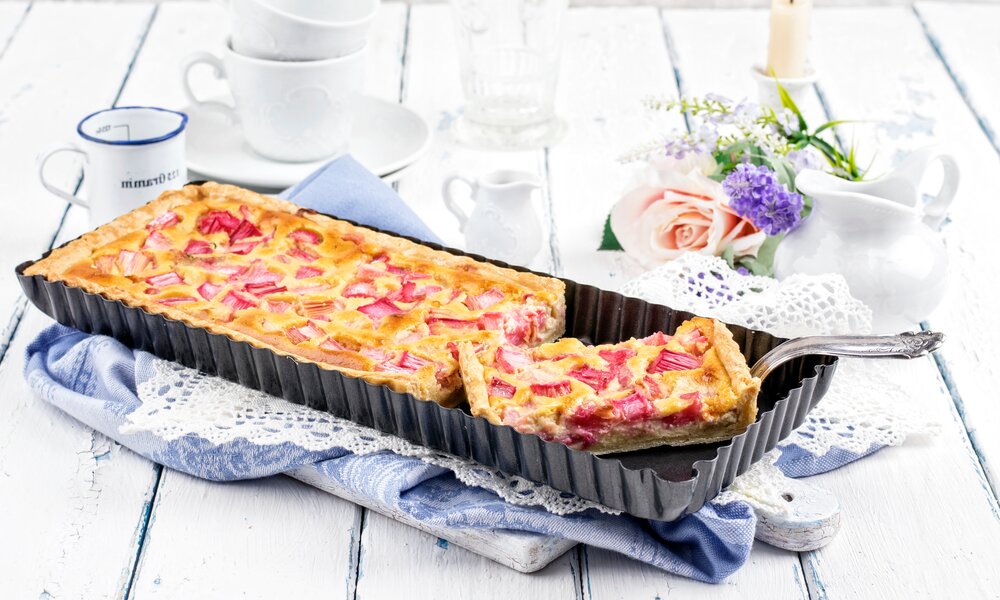 Rhaberkuchen in einer rechteckigen Backform, auf weißem Untergrund in Frühlingshafter Umgebung.  | © Adobe Stock / HLPhoto