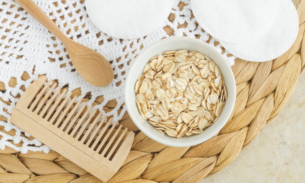 Wellness-Setup mit Haferflockenschale, Holzlöffel und Kamm auf gehäkeltem Tischset. | © Getty Images/ kazmulka