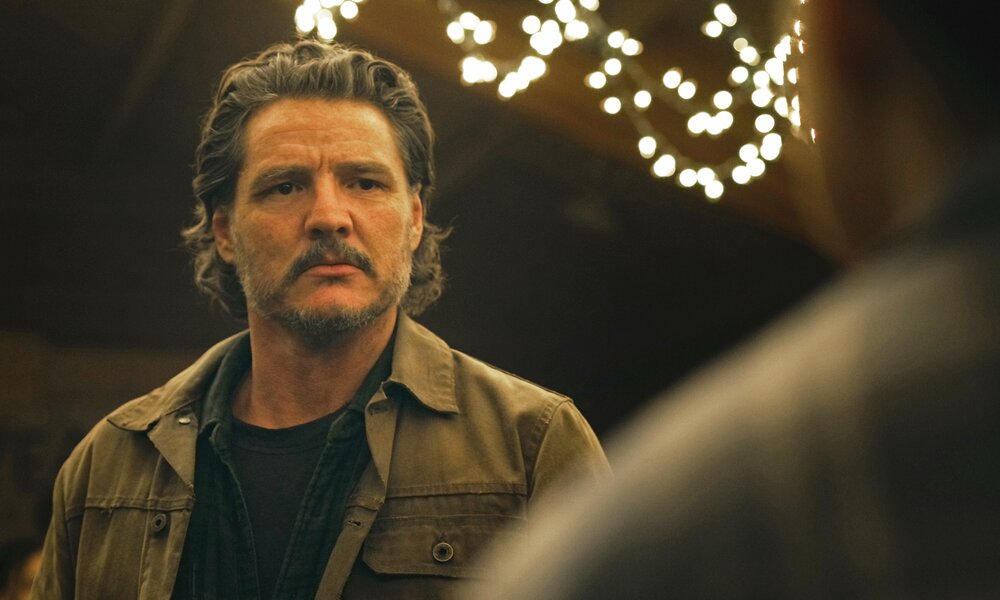 Pedro Pascal steht in einer Szene aus der HBO-Serie "The Last of Us" - Staffel 2 mit ernstem Gesicht bei Nacht unter einer Lichterkette. | © HBO/Sky