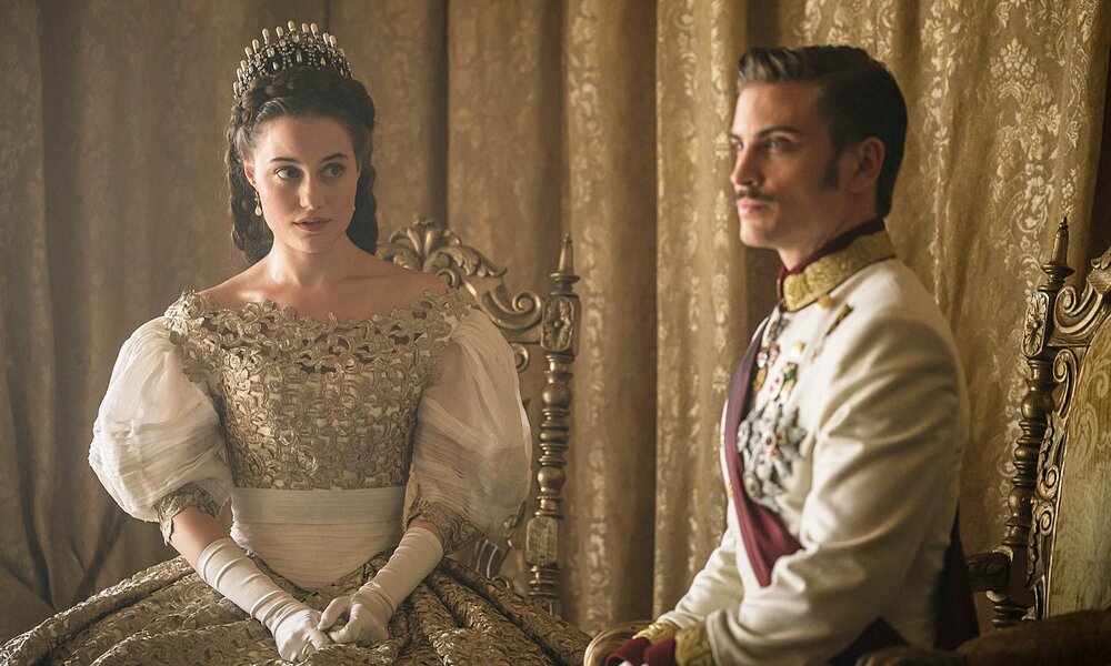 Dominique Devenport als Sisi und Jannik Schümann als  Franz Josef sitzen in kaiserlicher Kleidung nebeneinander in einer Szene aus der RIL-Serie "Sisi" | ©  RTL/Story House Pictures/Lukas Šalna