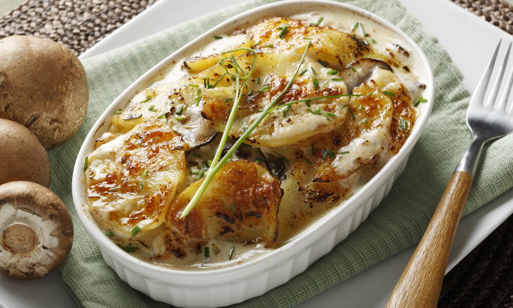 Kartoffelgratin in Auflaufform, darin enthalten außerdem gemischtes Gemüse und reichlich Fetakäse. | © Getty Images / 	Opticopia