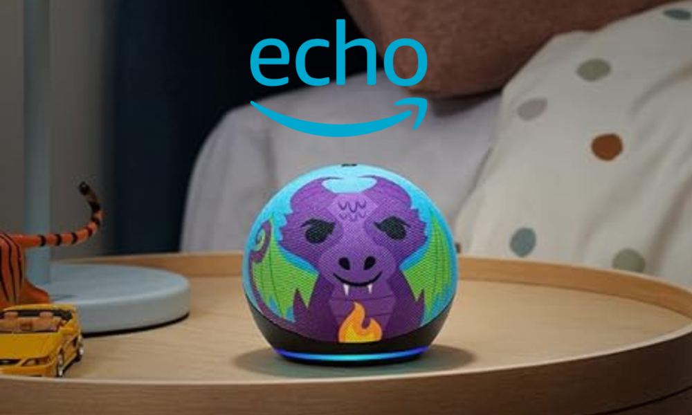 Amazon Echo Dot Kids mit lila Drachen-Design steht auf einem Holztisch, im Hintergrund eine gepunktete Bettdecke. | © Amazon
