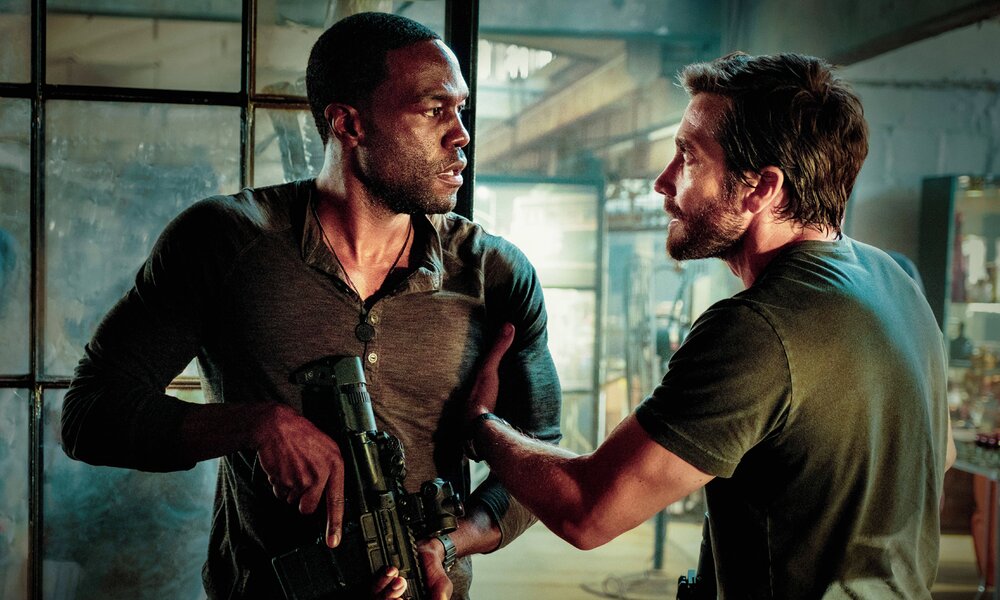 Yahya Abdul-Mateen mit Waffe in der Hand und Jake Gyllenhaal  diskutieren in einer Szene aus dem Kinofilm "Ambulance" | © Imgao Images/Picturelux