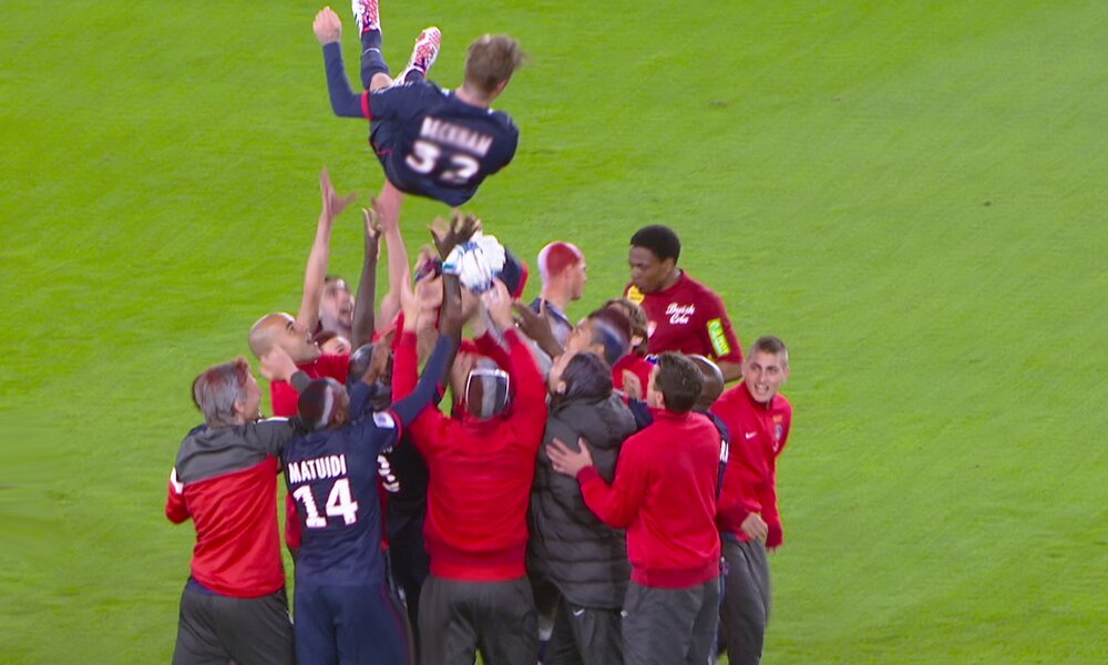 David Beckham wird von seinem Team auf dem Fußballfeld in die Luft geworfen und scheint über der Gruppe zu schweben in einer Szene aus der Netflix-Dokuserie "Beckham" | © Netflix
