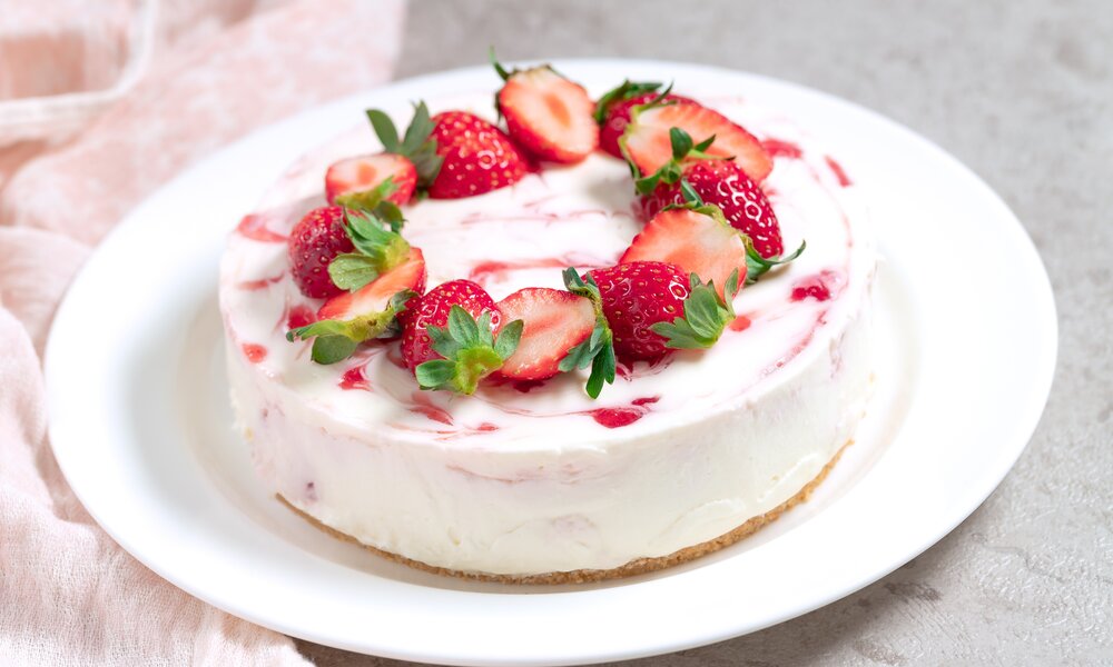 Erdbeer-Schmand-Torte ganz ohne Backen und Zucker angerichtet auf einem weißen Teller. | © Getty Images / yumehana