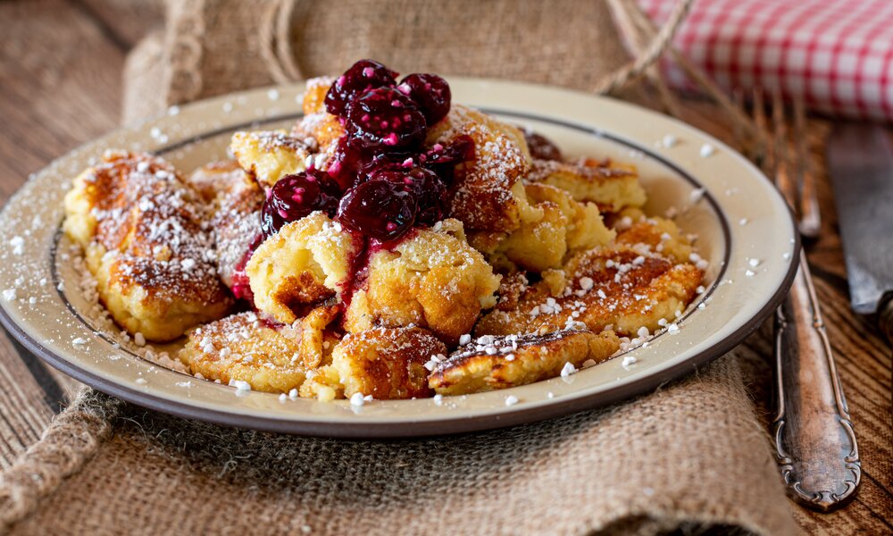 Fluffiger Kaiserschmarrn Low Carb ohne Zucker mit Puderzucker bestreut und mit heißen Kirschen garniert. | © Adobe Stock / Angelika Heine