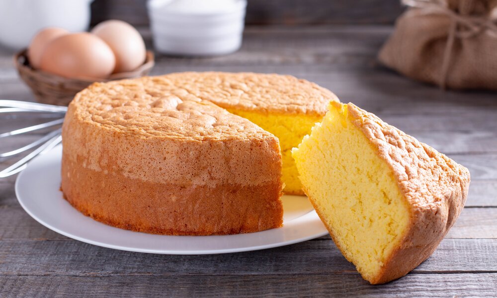 Angeschnittener Joghurtkuchen auf einem Teller angerichtet, ein Stück am Teller lehnend. | © Adobe Stock / qwartm