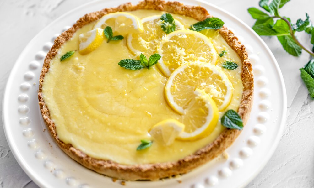 Angeschnittener Kuchen mit Zitronen belegt auf einem weißen Teller. | © Getty Images / lisegagne