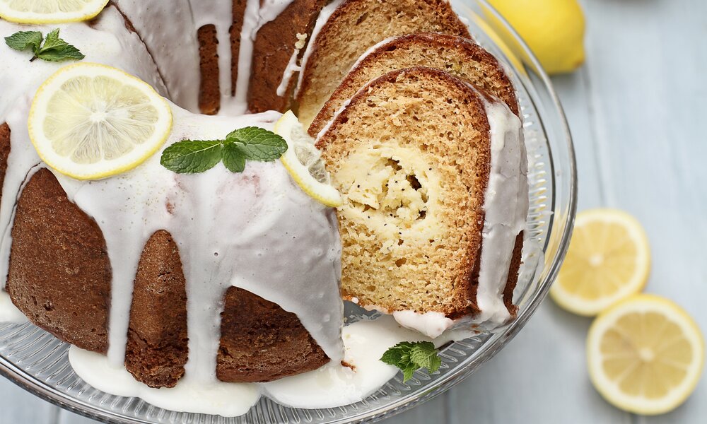 Zitronen-Joghurt-Gugelhupf mit Zuckerguss und frischen Zitronenscheiben belegt und mit frischen Minzblättern garniert. | © Getty Images / StephanieFrey