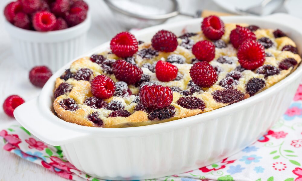 Quarkauflauf in Auflaufform, Himbeeren eingebacken, mit Puderzucker bestäubt. | © Getty Images / iuliia_n