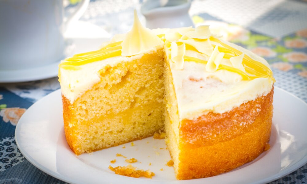 Angeschnittener Buttermilchkuchen mit Glasur auf einem weißen Teller angerichtet. | © Adobe Stock / lars