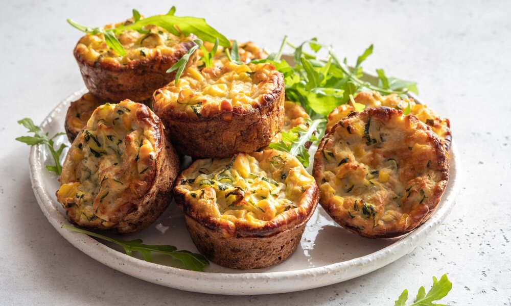 mehrere Zucchini-Muffins auf einem weißen Teller angerichtet und mit Petersilie garniert. | © Getty Images / Azurita