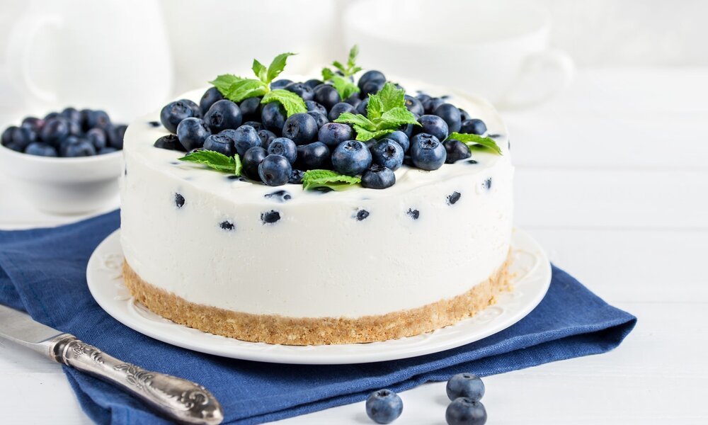 Angeschnittener Quarkkuchen belegt mit vielen frischen Blaubeeren. | © Getty Images / 	Anna_Shepulova
