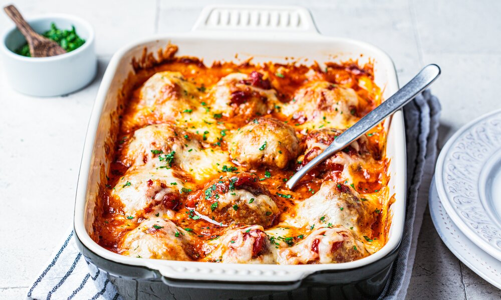 Low Carb Hackbällchen-Auflauf in Tomatensoße in Nahaufnahme in einer Auflaufform. | © Adobe Stock / vaaseenaa