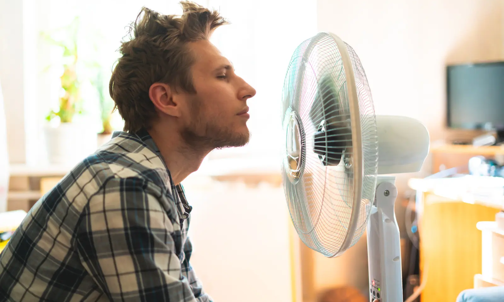 Mann kühlt sich vor einem Ventilator ab | © adobe.stock.com/Mihail