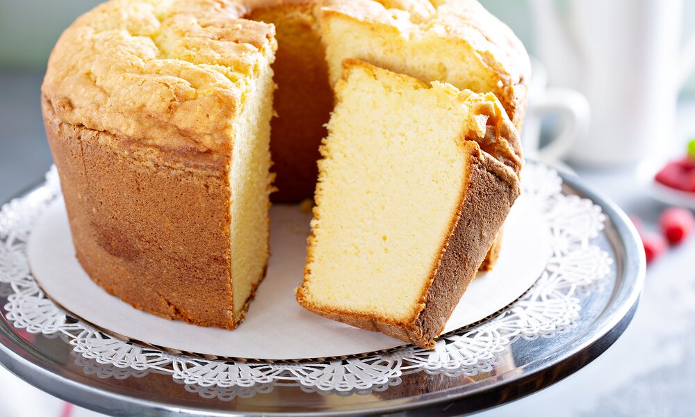 Angeschnittener fluffiger Schmandkuchen auf einem weißen Teller. | © Getty Images / VeselovaElena