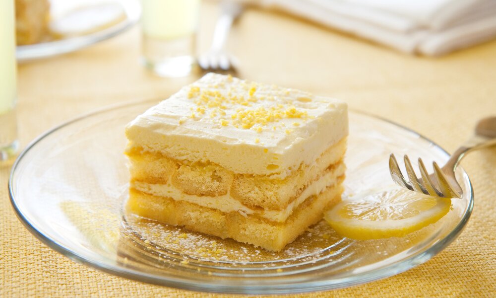 Ein Stück Zitronen-Tiramisu auf einem weißen Teller angerichtet, daneben eine Gabel. | © Getty Images / msheldrake