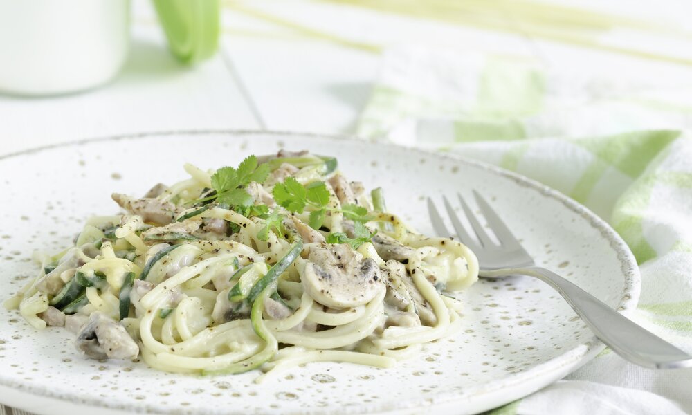 Auf einem Teller angehäufte Zucchininudeln mit Carbonara-Soße. | © Getty Images / gwenael le vot
