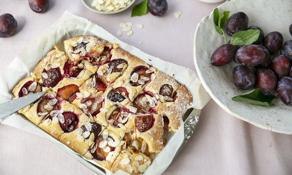 Pflaumenkuchen in Auflaufform neben frischen Pflaumen auf dem Teller. | © Getty Images / ©Tasty food and photography