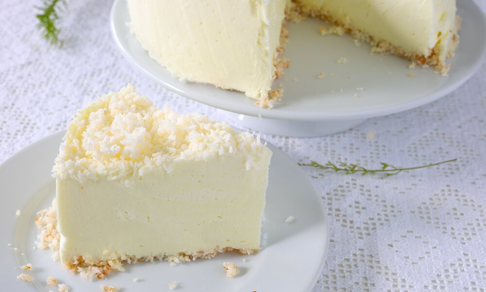 Angeschnittener Kokoskuchen, davor das Stück Kuchen. | © Adobe Stock / rainbow33