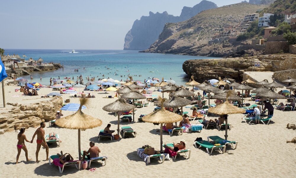 Ein weißer Sandstrand voller Stroh-Sonnenschirme auf Mallorca | ©  Getty Images / Andrew Fox