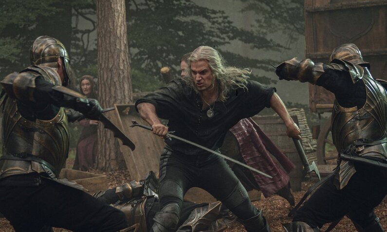Geralt von Riva schwingt sein Schwert gegen einen gegner vor sich und weht mit einer Axt einen Schlag von einem Gegner hinter sich ab. | © Netflix