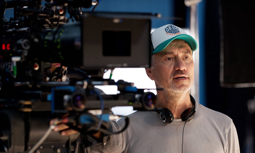 Der deutsche Regisseur Roland Emmerich an einem Filmset neben einer großen Filmkamera. | © ddp images/20thCentFox/Courtesy Everett Collection