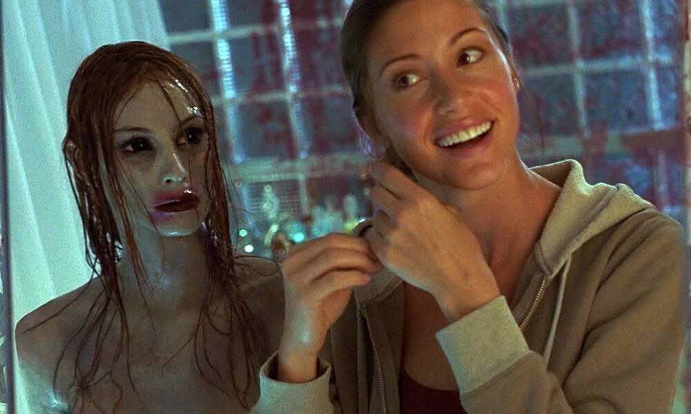 Eine junge, brünette Frau steht vor dem SPiegel und macht sich die Haare. Neben ihr steht ein weiblicher Geist, den die junge Frau nicht wahrnimmt. | © Warner Bros