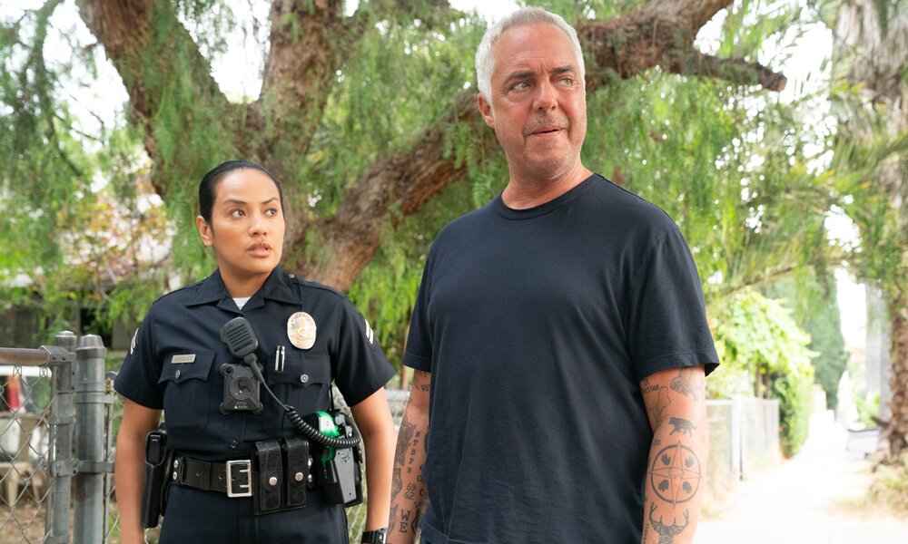 Denise G.-Sanchez in Polizeiuniform und Titus-Welliver iim dunklen Shirt stehen draußen auf der Straße in einer Szene der zweiten Staffel der Serie "Bosch: Legacy"  | © Freevee/Amazon/Warrick-Page