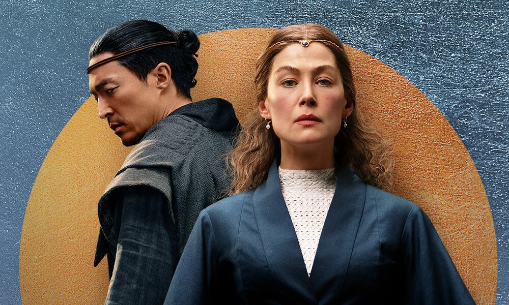 Daniel Henney als Lan Mandragoran steht hinter Rosamund Pike als Moiraine Damodred auf einem Plakat zur zweiten Staffel der prime Video serie "Das Rad der Zeit" - Staffel 2 | © Amazon Prime Video