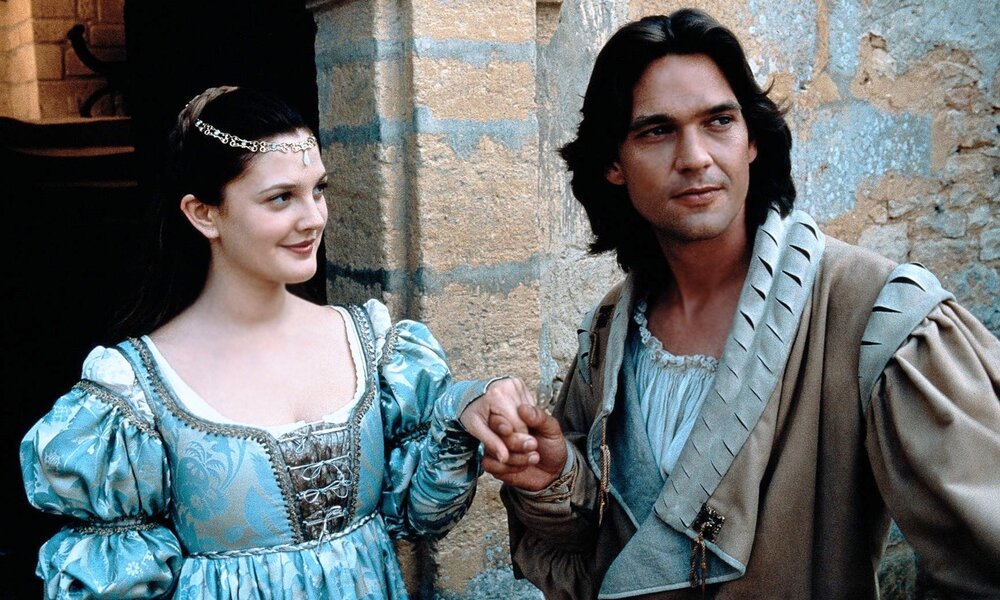 Drew Barrymore und Dugray Scott in prächtigen Mittelatergewändern stehen vor einer Mauer und halten Hänchen in einer Szene aus dem Kinofilm "Auf immer und ewig" | © ddp images