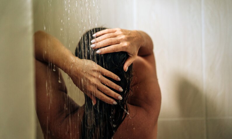 Frau steht unter Dusche | ©  Getty Images / Fiordaliso